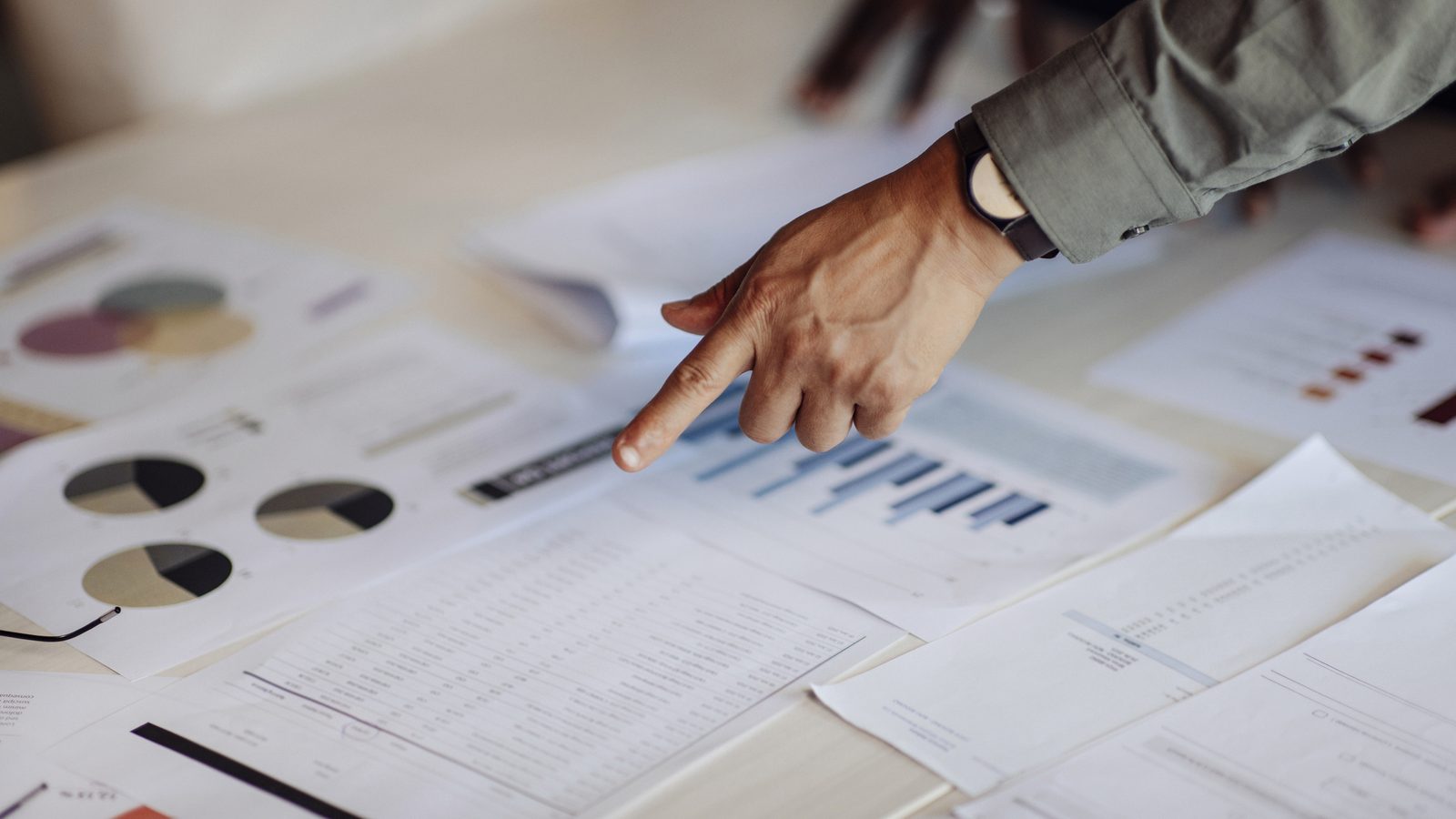 Hand pointing at printed charts and data reports on a desk reflecting how to evaluate an LSP AI capabilities and data accountability