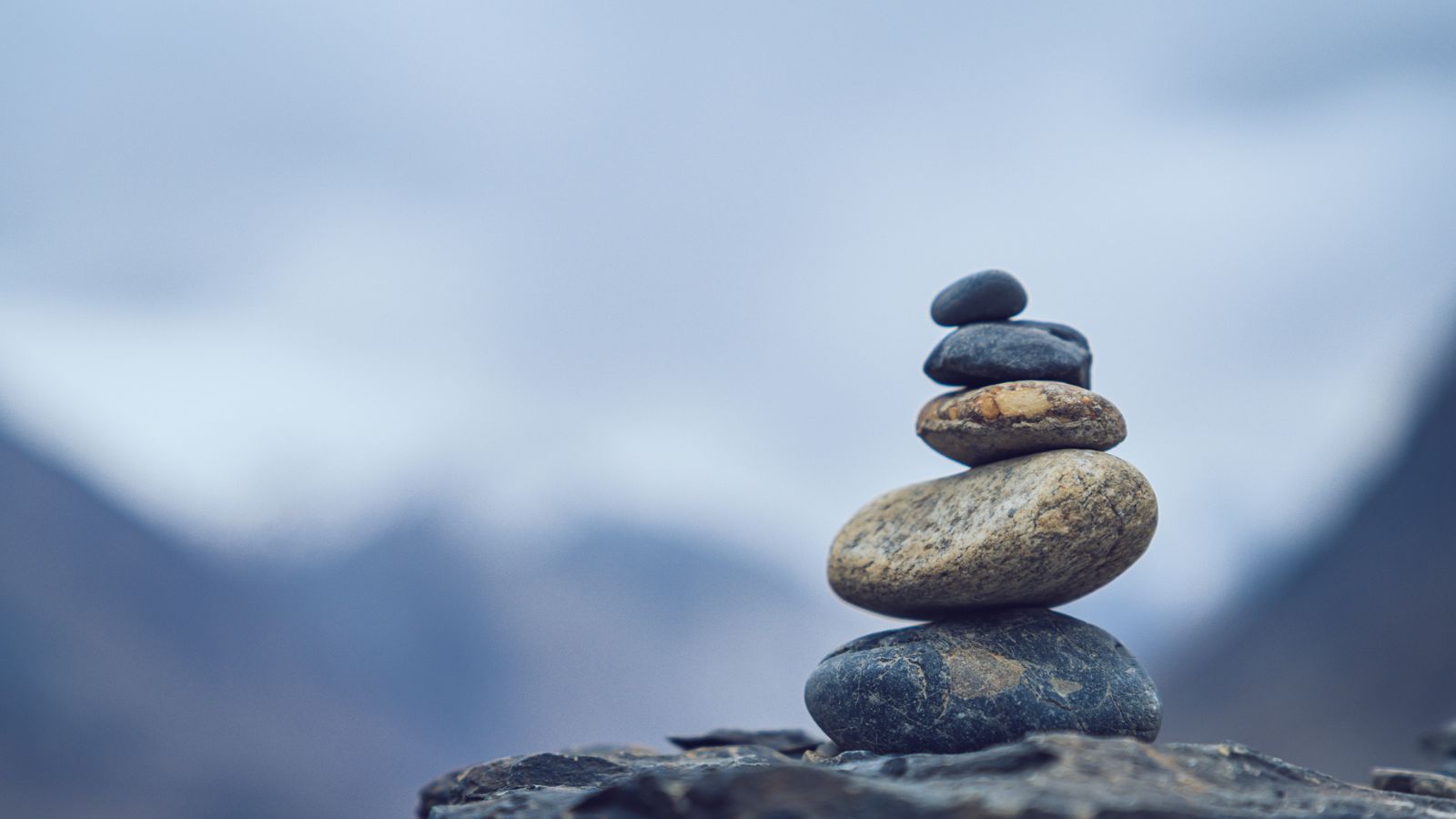A balanced stack of smooth stones against a mountain backdrop symbolizing the careful balance needed when drafting a translation services RFP