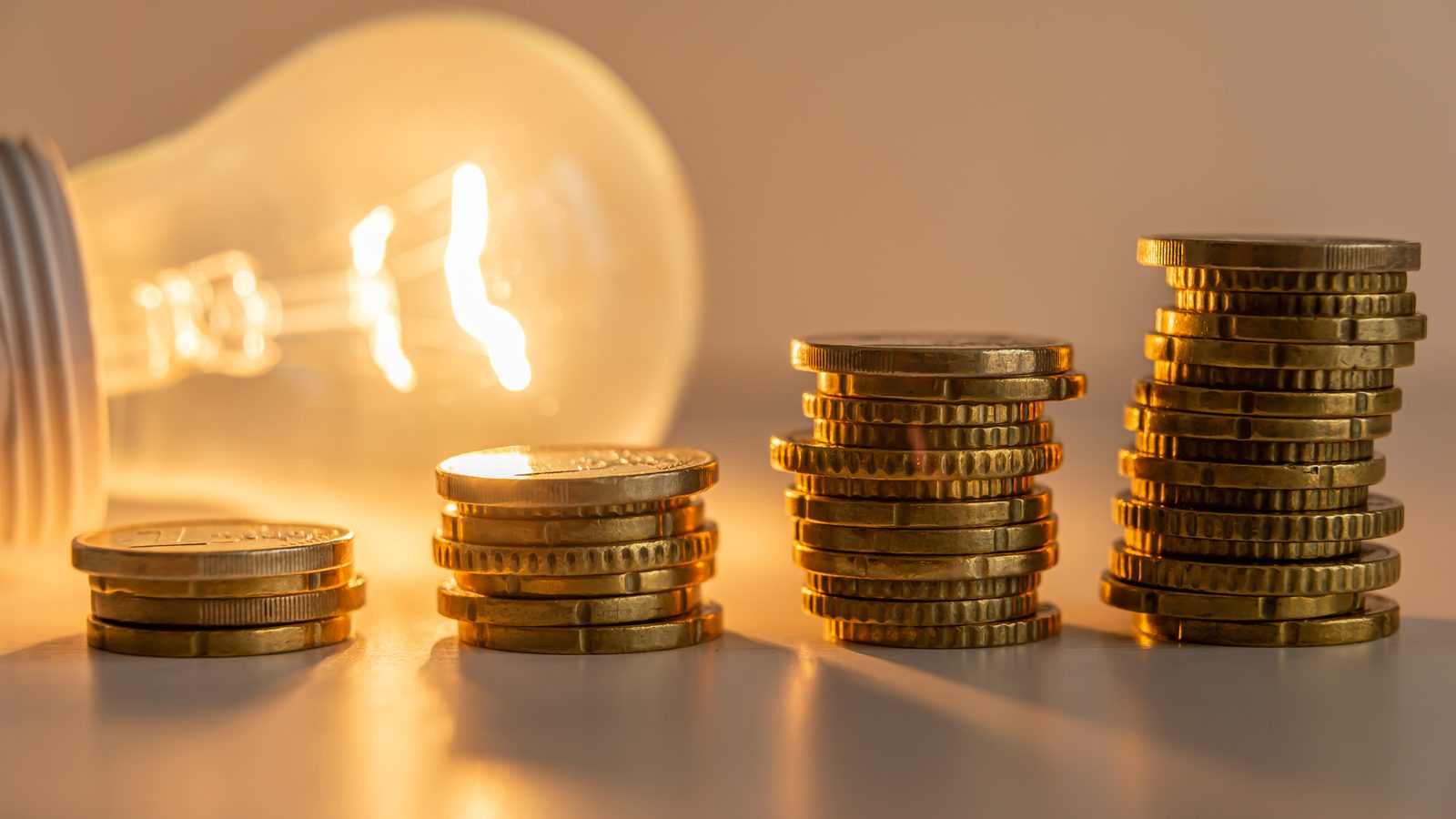A glowing lightbulb beside rising stacks of coins showing how hard it is to price domain expertise in localization purchasing
